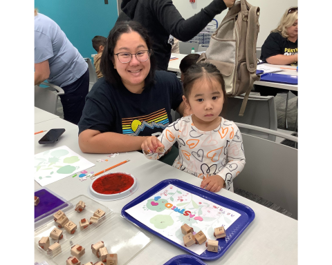 Caregiver and child creating a letter garden art piece with letter stickers and letter stamps.