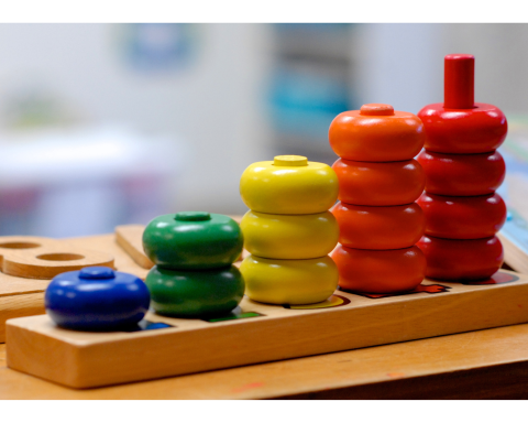 Counting toy with colorful round wooden pieces on pegs, from one to five.