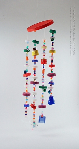 Windchime made of plastic lids and pony beads hanging in front of a white background