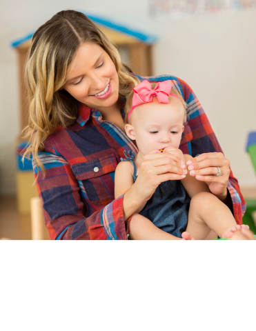 Female caregiver signing "more" with child in lap.