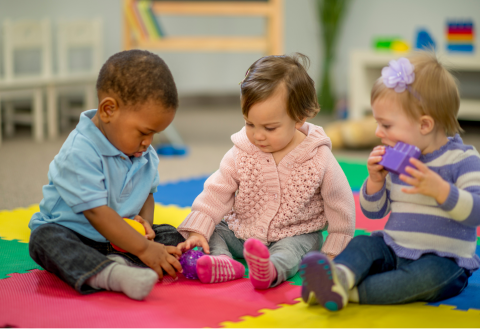 Three young toddlers playing with toys.