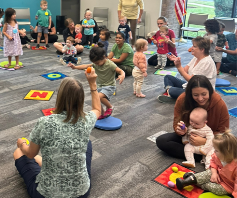 Adults and young children shaking eggs at storytime.