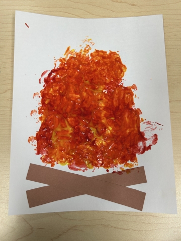 A painted campfire with brown strips of construction paper as the logs.