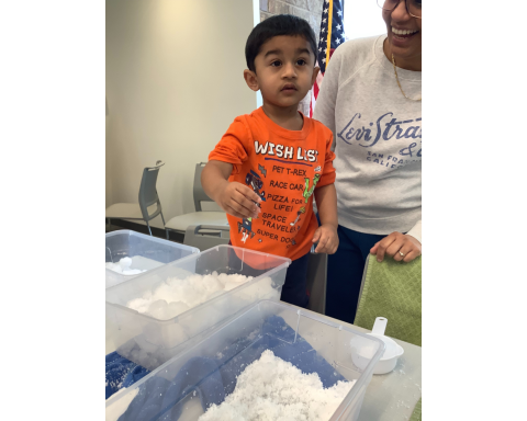 Child with bins full of snow or fake snow.