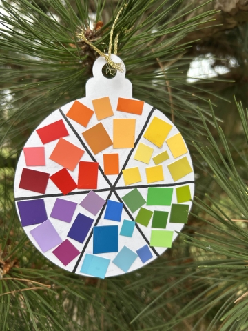 A paper ornament decorated with paint chips to create a color wheel.