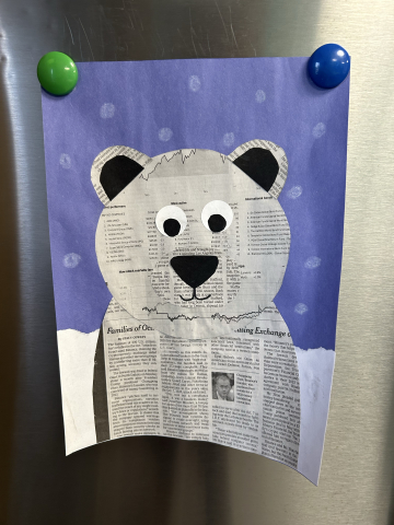A 2D polar bear made out of newspaper glued onto a snowy background.