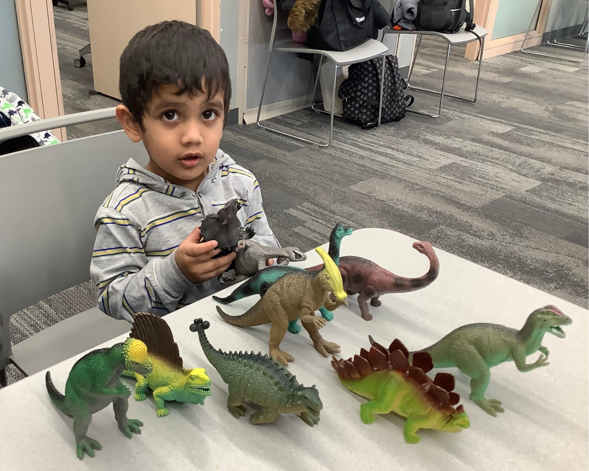 Child playing with large dinosaur figurines.
