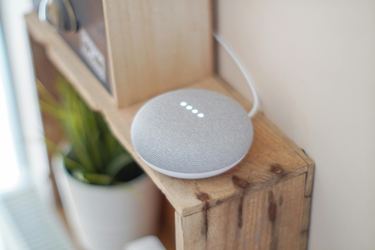 A round grey speaker on a brown board.