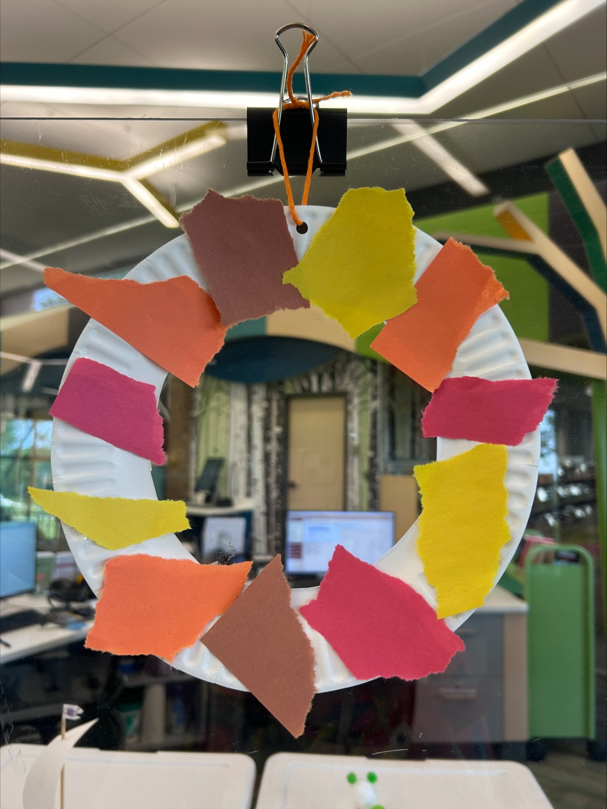 A paper plate wreath with torn pieces of construction paper as decoration.