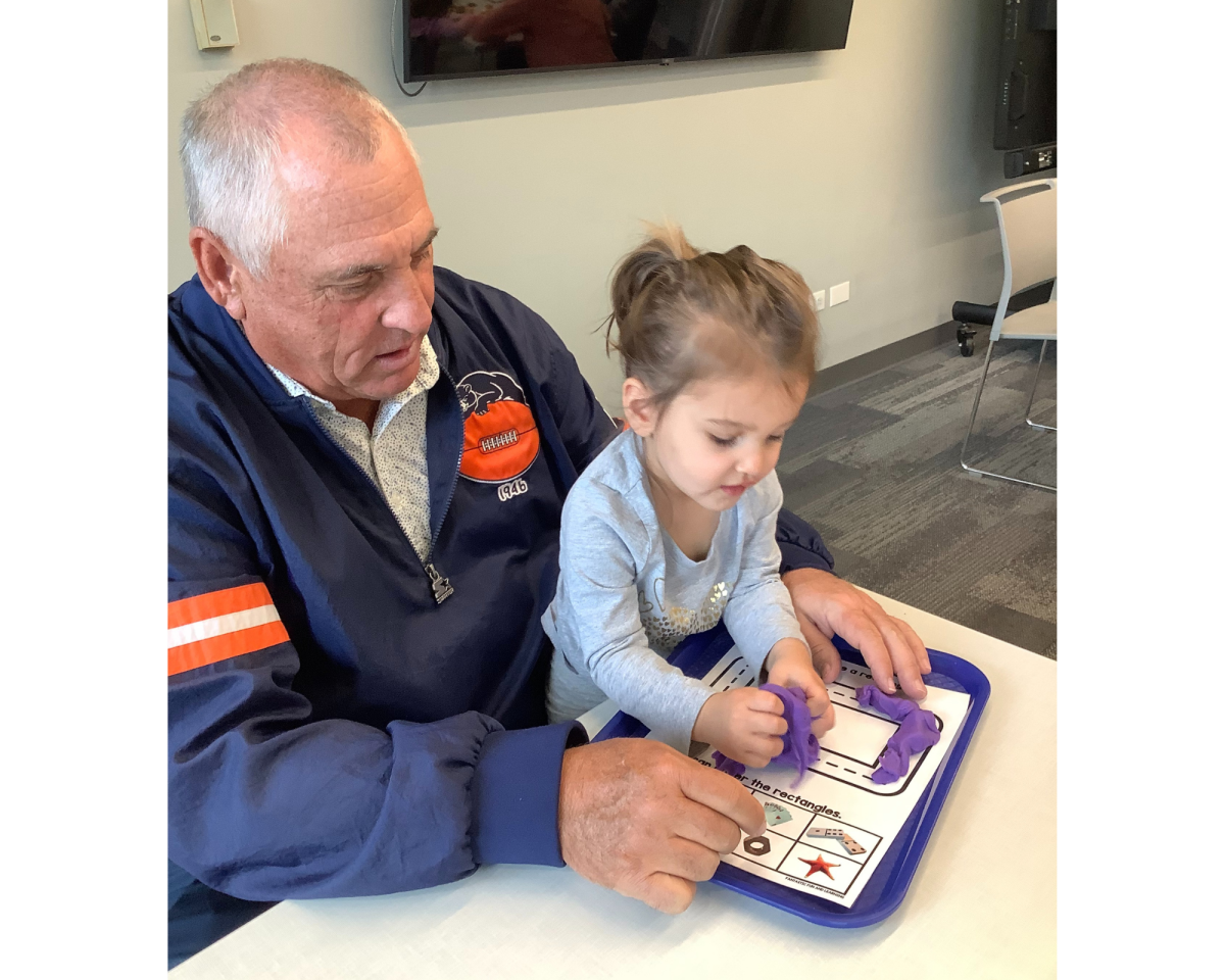 Child and grandfather playing with a shapes matching activity.