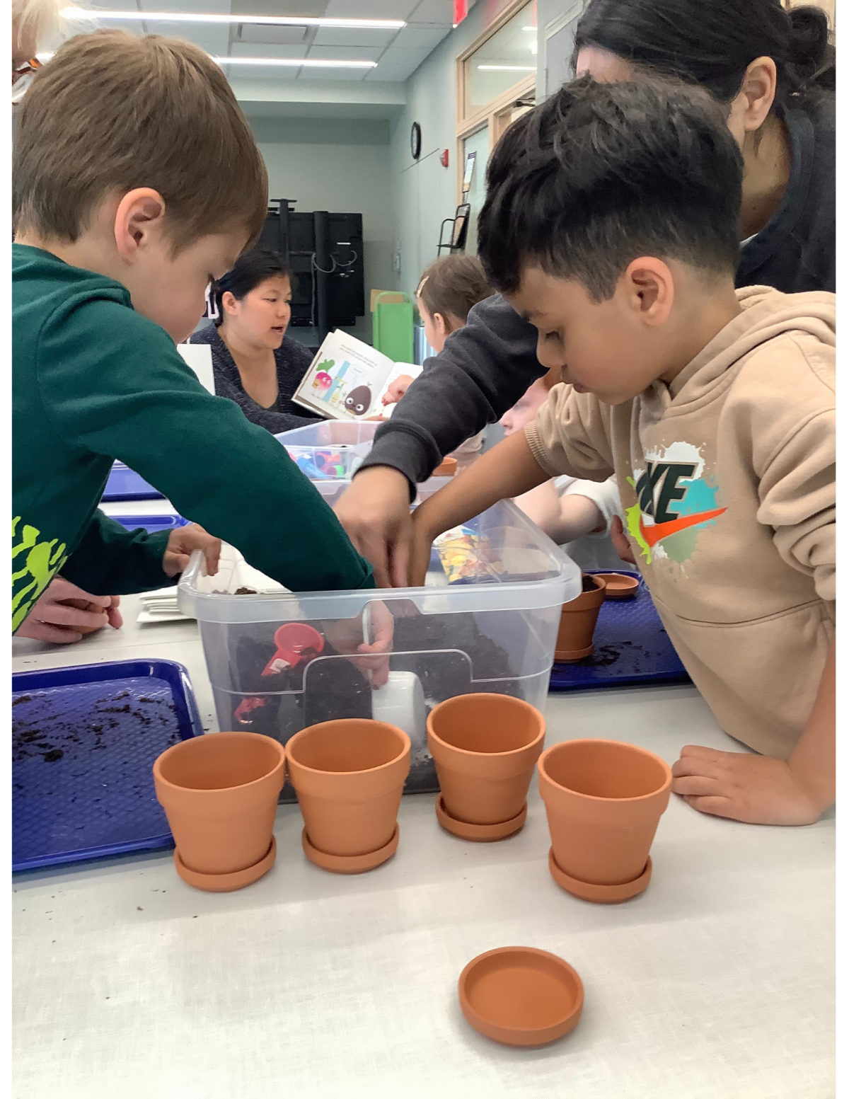 Children scooping potting soil into small planter pots.