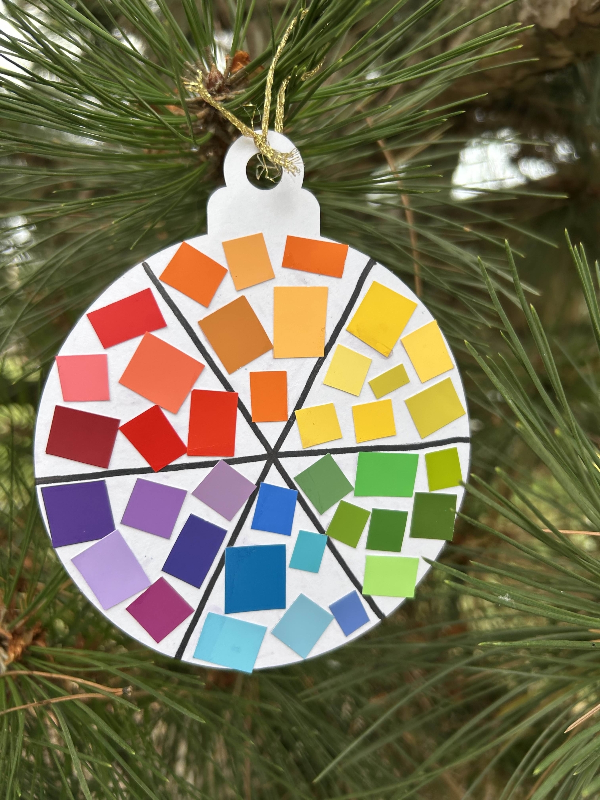 A paper ornament decorated with paint chips to create a color wheel.